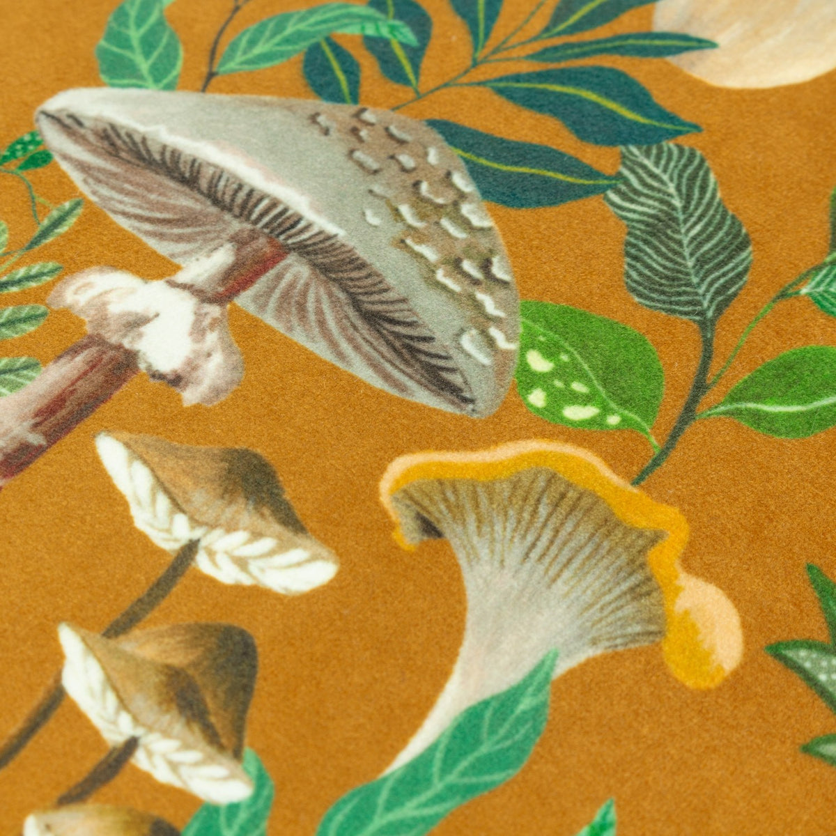 Close-up of the Wildgarden Mushroom polyester cushion in amber-gold, showing velvet-fronted print of toadstools, chanterelles and green foliage detail.