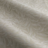 Close-up of Willow Boughs jacquard linen pencil pleat curtain fabric in beige, showing a woven trailing leaf pattern with tonal relief across soft folds.