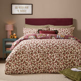 Wild Card Reversible Animal Duvet Cover Set shown on a bed with pink, brown and cream leopard print facing up, styled in a burgundy-toned bedroom.