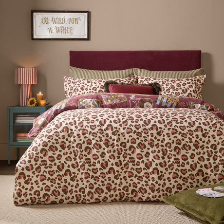Wild Card Reversible Animal Duvet Cover Set shown on a bed with pink, brown and cream leopard print facing up, styled in a burgundy-toned bedroom.