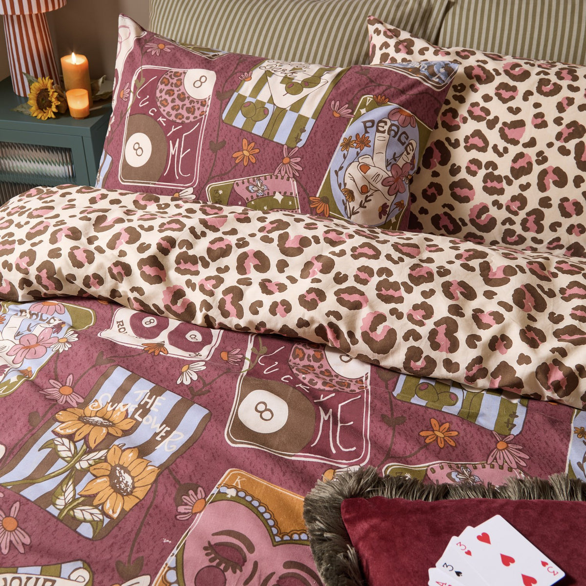 Wild Card Reversible Animal Duvet Cover Set in burgundy, styled on a bed showing tarot-inspired print and reverse pink, brown and cream leopard print with matching pillowcases.