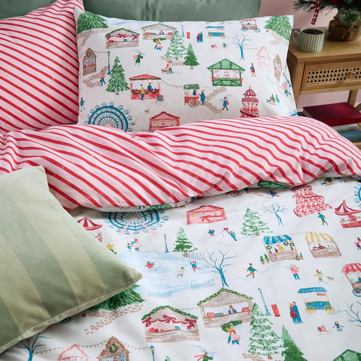 Reversible cotton duvet cover set with a festive fairground and Christmas tree print on one side, red-and-cream candy stripes on the other, plus matching pillowcase.