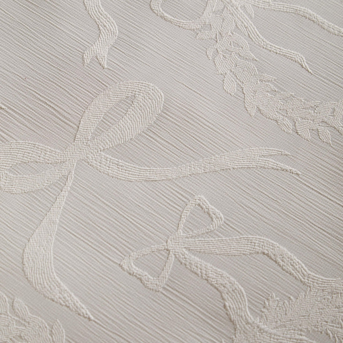 Close-up of the Winter Wreath Duvet Cover Set showing a woven jacquard pattern of bows, ribbons and wreaths in raised relief on a cream-white ground.