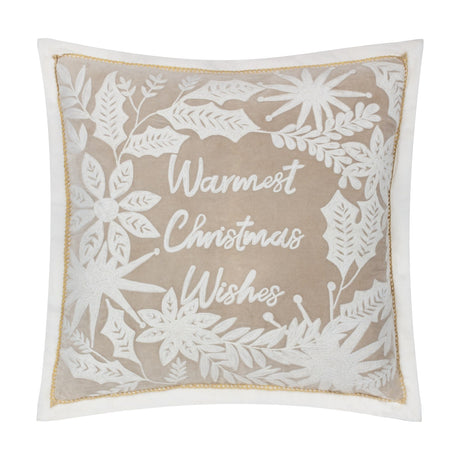Square natural beige velvet cushion with white embroidered "Warmest Christmas Wishes" script, framed by holly, leaves and starburst motifs, white piping trim, on a plain white background.