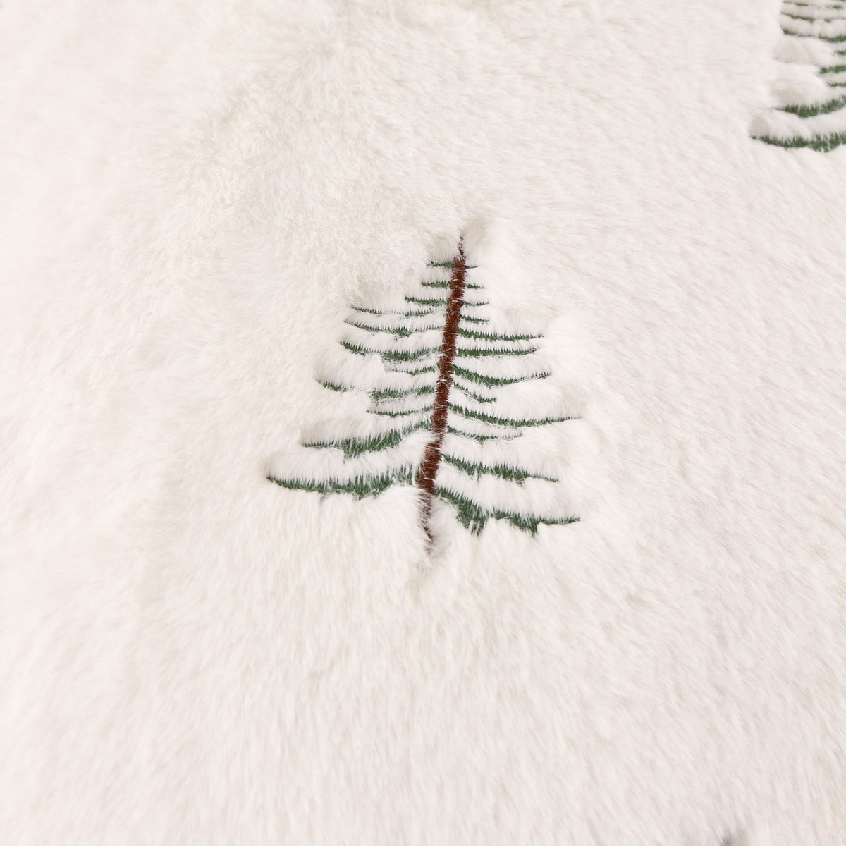 Close-up of the Winter Pines Woodland Polyester Throw in ecru, showing soft fleece fabric with a raised embroidered pine tree in green and brown thread.