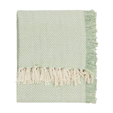 Wisley Herringbone Polyester Throw in leaf green, folded to show chevron weave texture and cream knotted tassel fringe, on a plain white background.