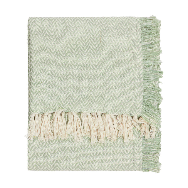 Wisley Herringbone Polyester Throw in leaf green, folded to show chevron weave texture and cream knotted tassel fringe, on a plain white background.