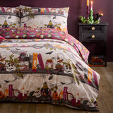 Reversible Witchy Tales Duvet Cover Set on a bed, cream Halloween side with skulls, pumpkins, spell books and jars, deep pink reverse, in a dark candlelit bedroom.