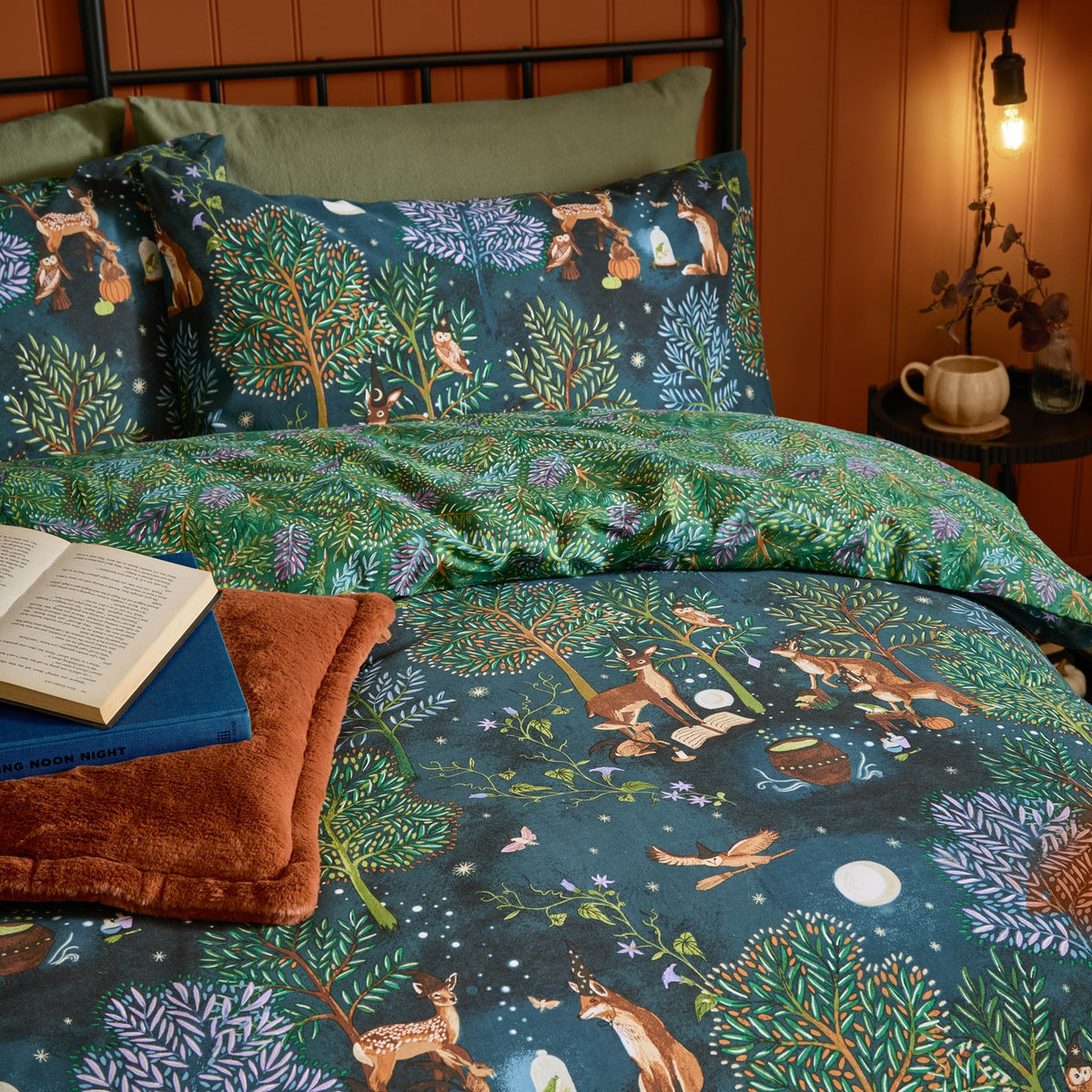 Woodland Ritual Printed Reversible Duvet Cover Set in Navy, styled on a bed showing the woodland animal print side with matching pillowcases in a warm-toned bedroom.