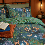 Woodland Ritual Printed Reversible Duvet Cover Set in Navy, styled on a bed showing the woodland animal print side with matching pillowcases in a warm-toned bedroom.