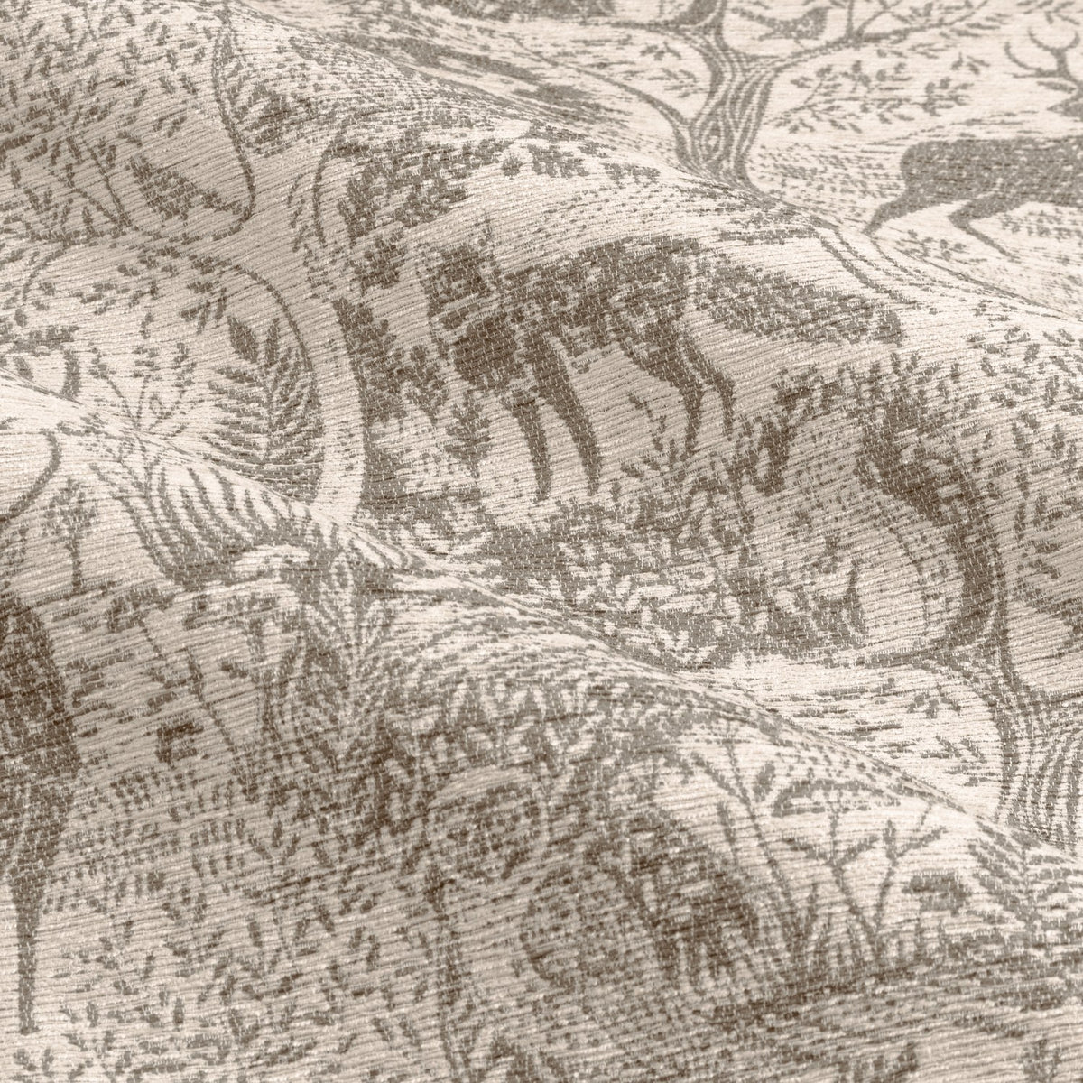 Close-up of Winter Woods eyelet curtain fabric in taupe, showing a woven chenille jacquard pattern of deer, hares, birds and trees on a pale ground.