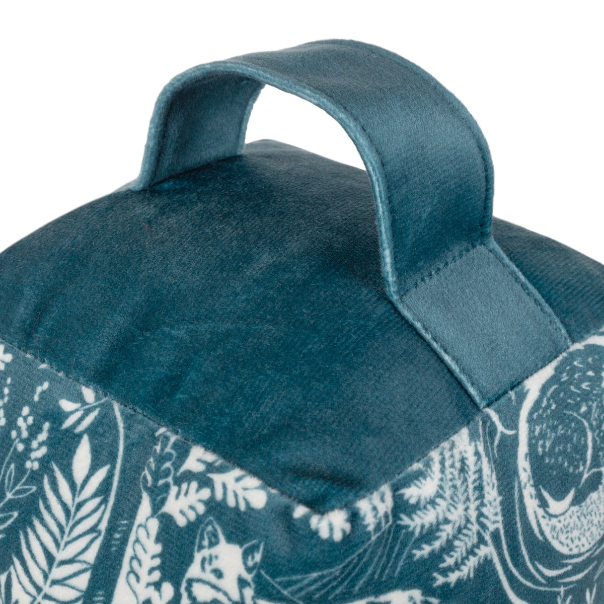 Close-up of the Winter Woods Animal Velvet Door Stop in midnight blue, showing the stitched carry handle and woodblock-style forest animal print in cream on velvet fabric.