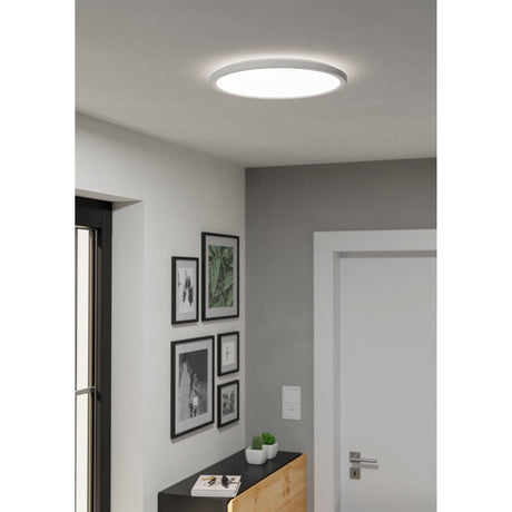 Rovito LED Flush Ceiling Light, round white 38.9cm fixture with opal shade, shown glowing on a hallway ceiling above framed wall art.