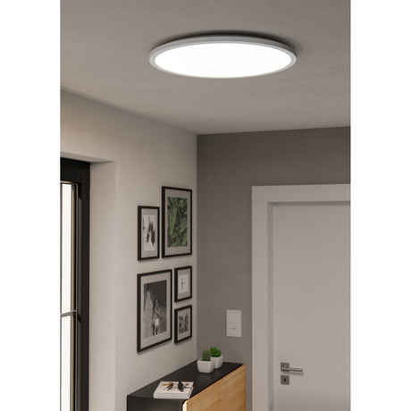 Rovito Smart Colour Changing LED Flush Ceiling Light, 50cm round white plastic fixture mounted in a hallway ceiling above a gallery wall of framed prints.