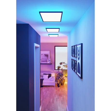 Rovito Smart LED Panel Lights in black frames with rectangular diffusers fitted flush to a hallway ceiling, glowing blue to complement the adjoining room's lit decor.