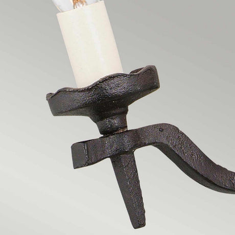 Close-up of a wrought iron candle holder with a medieval design, featuring a curved arm and scalloped base. The piece boasts a textured finish against a light gray background, reminiscent of the elegance found in the Rectory 2 Light Wall Light - Black.