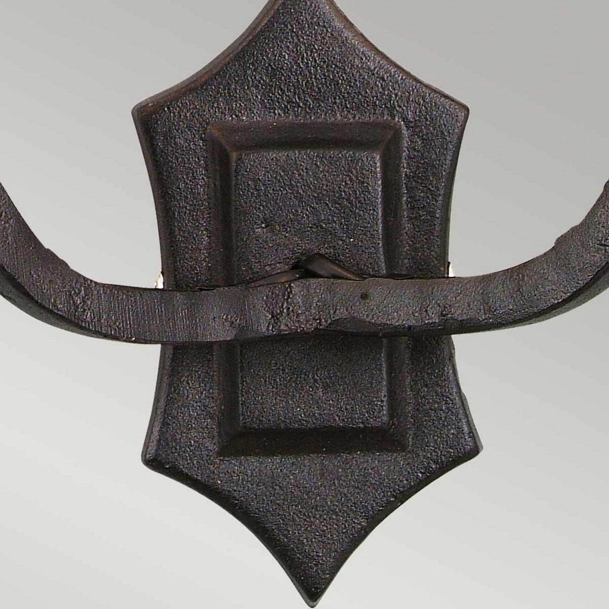 Close-up of a decorative black wrought iron door knocker with a shield-shaped backplate, showcasing a medieval design. The rustic, textured look features a curved handle, reminiscent of the craftsmanship found in the Rectory 2 Light Wall Light - Black. The background is a neutral light gray.