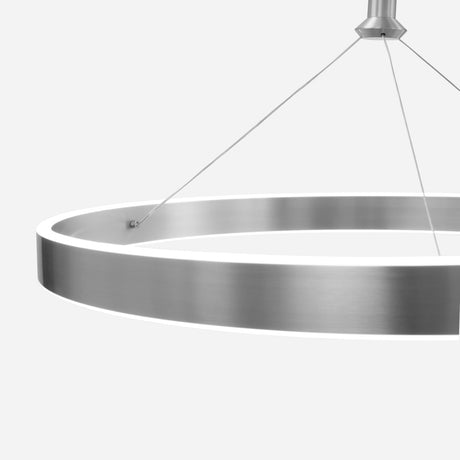 The Aurora LED Suspension Light - Matte Silver, a modern masterpiece with a matte silver finish, is suspended from the ceiling by thin cables. Its dimmable feature emits a soft glow, beautifully contrasting against the minimalist white background.