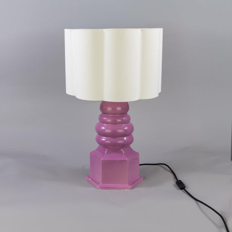 Safi ceramic table lamp with a glossy Carnation Pink stacked, tiered base on a hexagonal plinth, topped with a scalloped cream fabric drum shade, shown on a plain grey background.