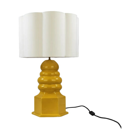 Safi Ceramic Table Lamp with a white scalloped drum shade on a mustard yellow glazed ceramic base featuring stacked rounded tiers and a hexagonal plinth, shown on a plain white background.