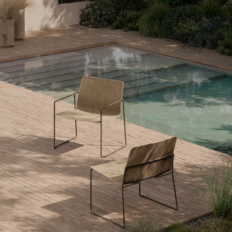 Sal Steel Stacking Garden Lounge Chairs with armrests beside a pool, woven beige and brown fabric seats on sled-style steel frames with a green-grey finish.