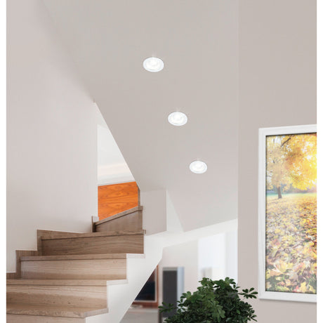 Three round white Salabate LED downlights recessed into a sloped stairwell ceiling, each with a translucent rim, in a hallway setting with wooden stairs and framed art.
