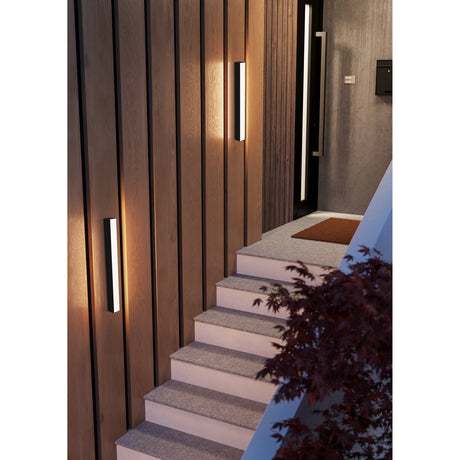 Salitta LED Downlight 58cm in black mounted vertically on wood-panelled walls beside a staircase, casting a warm white glow down each slim aluminium bar.