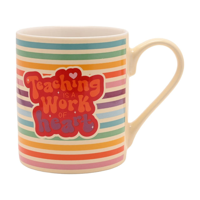 Porcelain mug with rainbow-striped cream body and a red "Teaching Is A Work Of Heart" badge design, cream handle, shown on a plain white background.