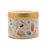 Round gold tin scented candle with cream label printed with classroom icons—glue, scissors, pencils, books, paperclips—and a gold lid, shown on a white background.