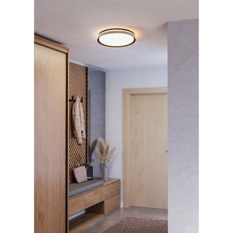 Seluci LED Flush Ceiling Light in black with white diffuser and silver-tone band, illuminated on a hallway ceiling above a wooden wardrobe and bench.