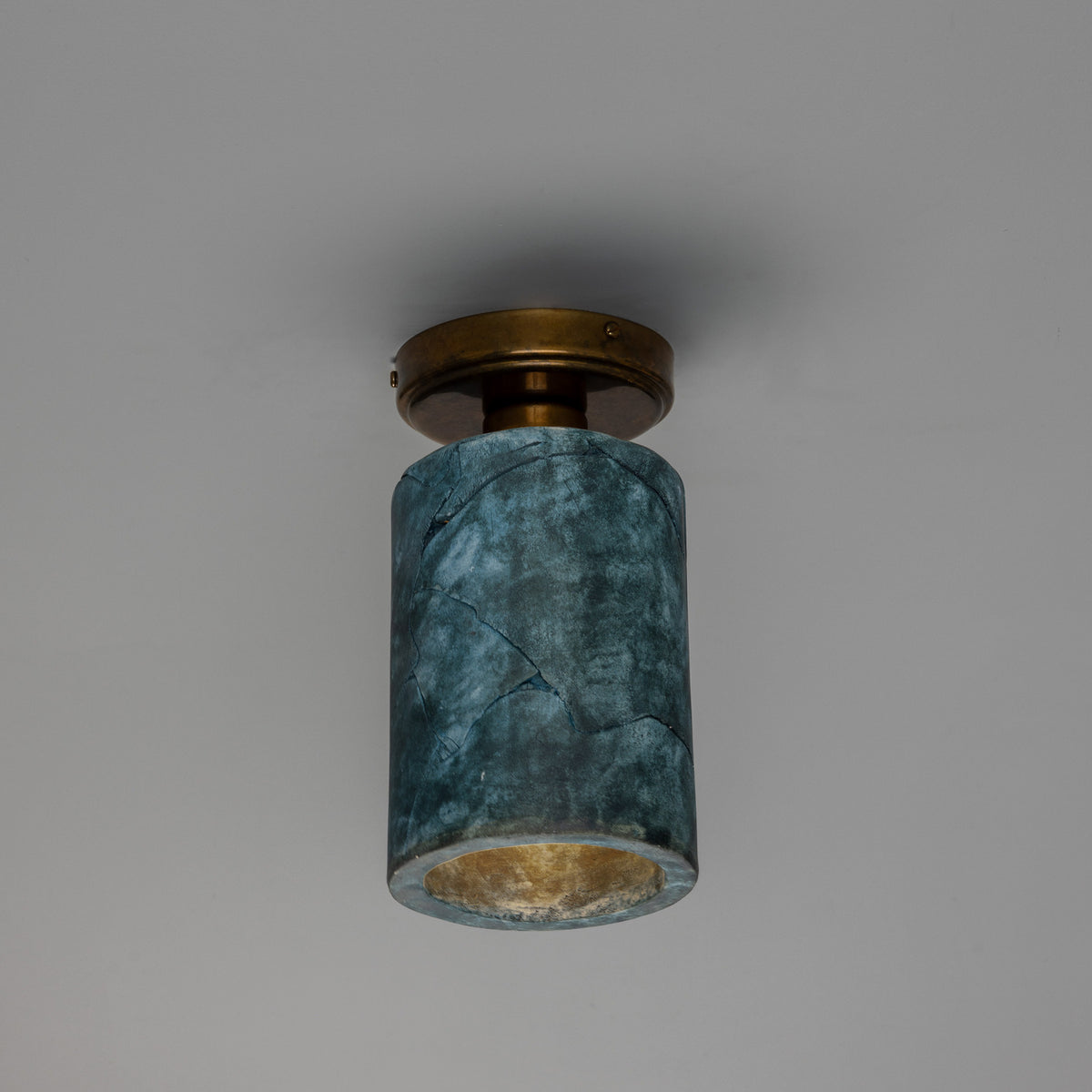 Senna Ceramic Ceiling Light in Blue Earth glaze, a cylindrical ceramic shade with crackled texture on a round brass ceiling canopy, shown against a plain grey background.