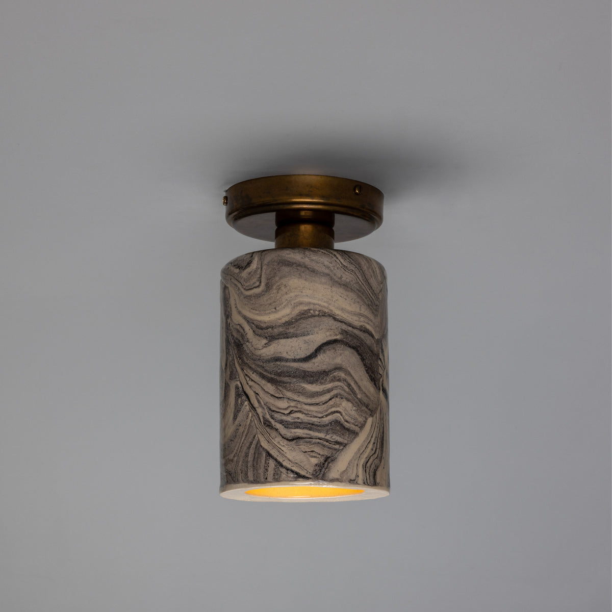 Senna Ceramic Ceiling Light in marbled grey and cream, slim cylindrical shade beneath a round brass canopy, open base with visible E27 bulb, shown against a plain light grey background.