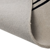 Sesulu Circle Pattern Rug 300 x 200cm, corner folded back to show beige pile and woven backing with black stripe pattern visible along the edge.