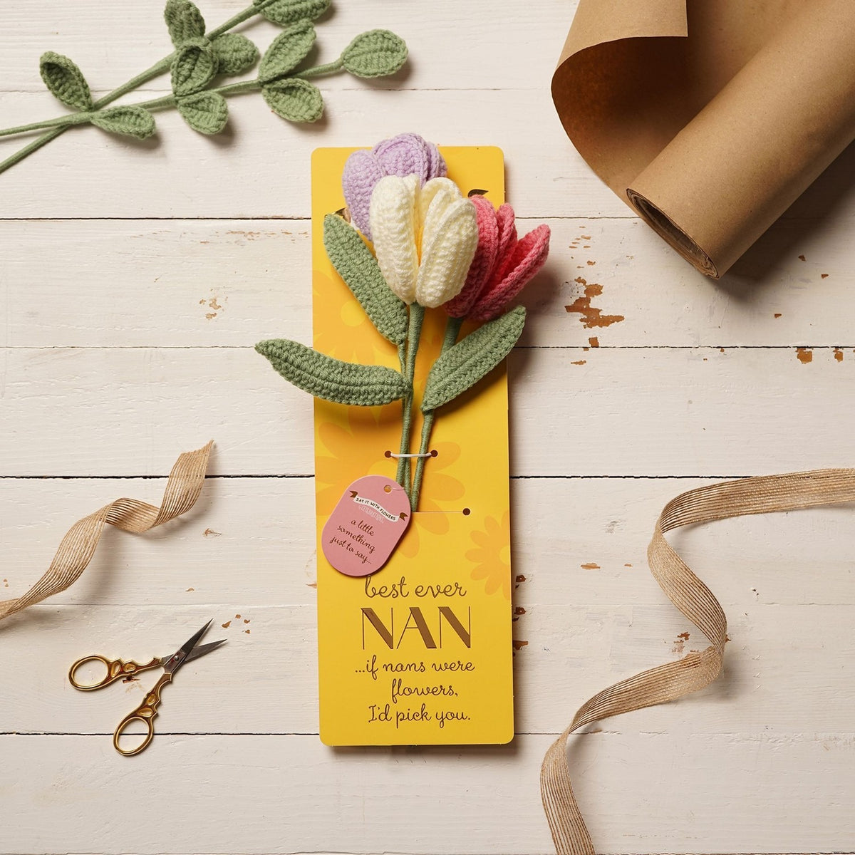 Crochet tulip flower bundle with lilac, cream, and pink blooms on sage-green stems, mounted on a yellow "Best Ever Nan" message card, styled with ribbon and kraft paper.