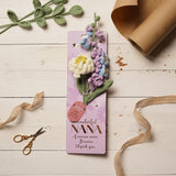 Wonderful Nana Peony and Foxglove Crochet Flower Bundle on lilac card with pink tag, shown on a white wooden surface with ribbon and kraft paper.