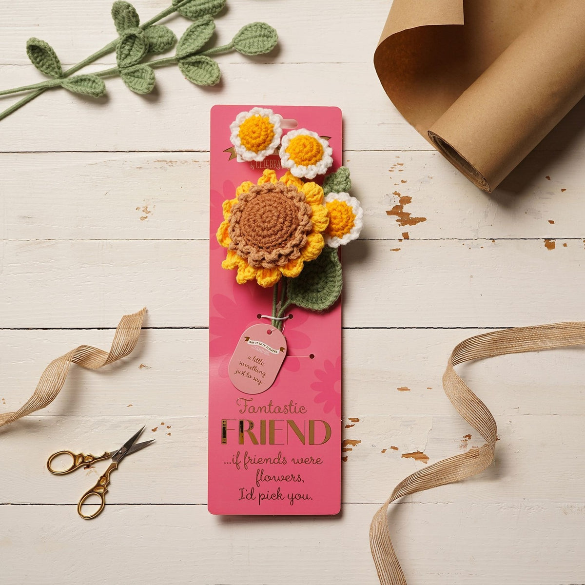 Crochet flower bundle on pink "Fantastic Friend" card, featuring one brown-centred yellow sunflower and three white-and-yellow daisies with green leaves, displayed on a wooden surface.
