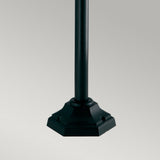 Introducing the Shannon 1 Light Pillar - Black, a sleek metal pole with a decorative hexagonal base, perfect for outdoor lighting applications. Set against a plain gray background, this pillar boasts a smooth, corrosion-proof finish and features subtle detailing around its weather-resistant base.