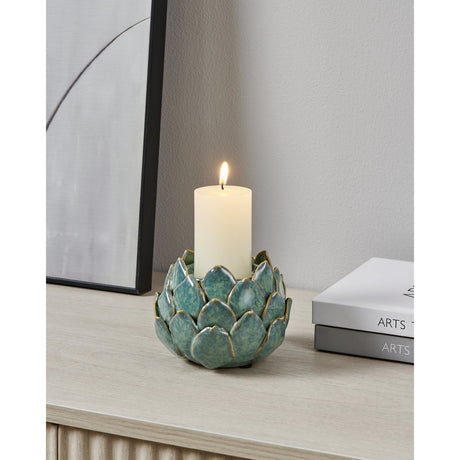 Shigay ceramic candle holder in light green, artichoke-shaped with layered petals and brown-edged detailing, holding a lit pillar candle on a wooden sideboard.