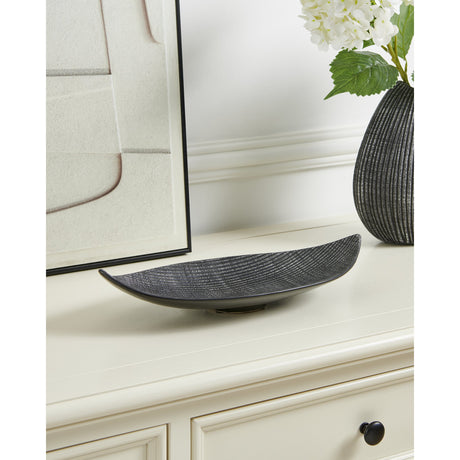 Shiguhe ceramic decorative plate in a long, upturned leaf shape, black with silver-brushed ribbing, shown on a cream sideboard beside a mirror and vase.