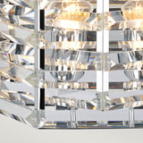 Detail of the Shoal 2 Light Wall Light in polished nickel, showcasing its geometric crystal design with visible bulbs and interwoven crystals. The fixture displays several horizontal, reflective strips that produce a layered appearance on its sleek frame, emitting a warm glow through its translucent elements.