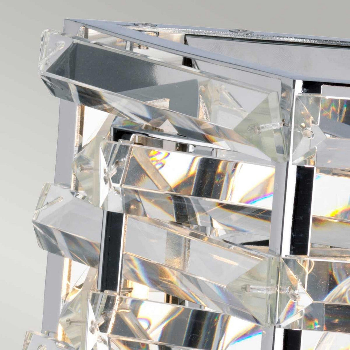 Close-up of the Shoal 2 Light Wall Light, featuring intertwining crystals elegantly arranged within a polished nickel frame. Light reflects through the prisms, casting vibrant rainbow hues that enhance its sleek, contemporary design.