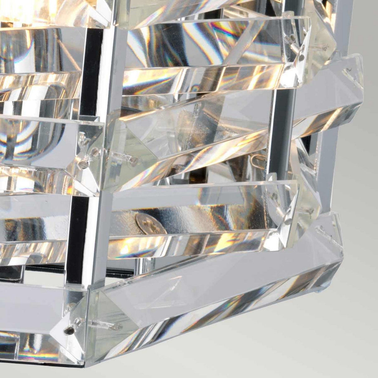 Detailed view of the Shoal 2 Light Wall Light - Polished Nickel, showcasing a sleek frame with clear, angular glass panels. The glass beautifully reflects light, producing vibrant prism effects as intertwined crystals introduce a touch of elegance against soft gray shades.