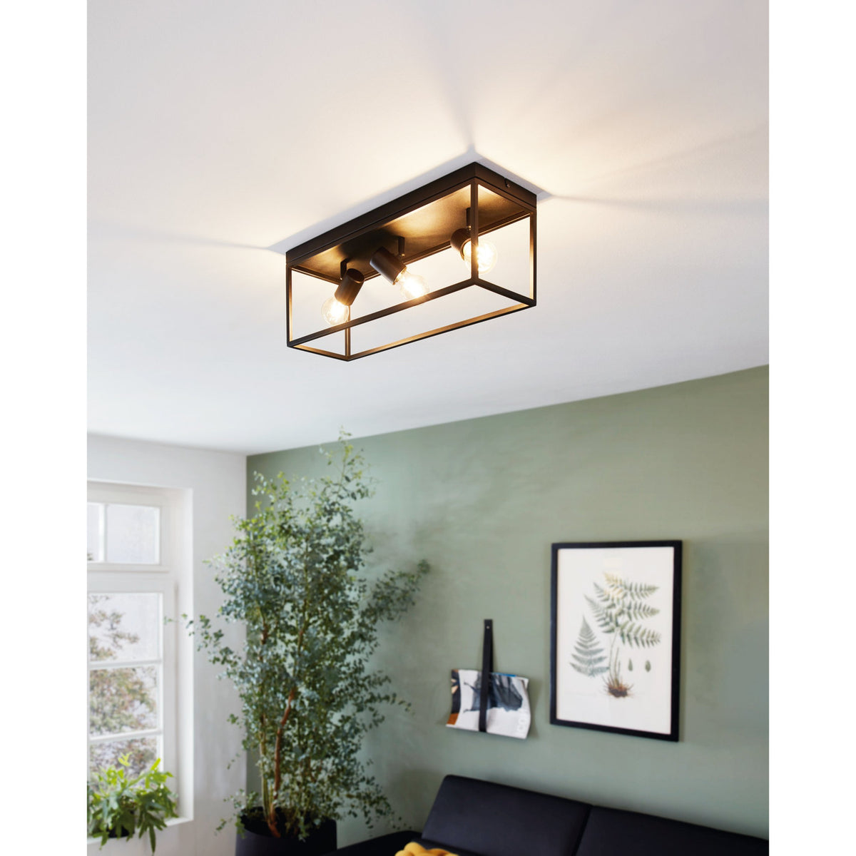 Silentina 3 Light Ceiling Light in black steel with an open rectangular cage frame and three adjustable E27 spotlight heads, shown fitted in a living room with green walls.