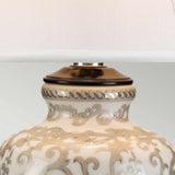 A close-up of the Silver Thistle 1 Light Table Lamp showcases a ceramic base adorned with subtle floral designs in neutral shades, complemented by a pristine white fabric lampshade.