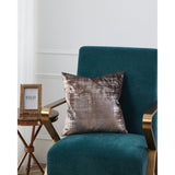 Singu Cushion in brown and silver with a distressed metallic pattern, 45x45cm polyester cover, shown on a teal armchair beside a gold side table.