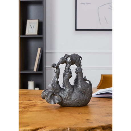 Siocon Elephant Ornament in silver and black polyresin, showing a mother elephant on her back balancing her calf on her raised feet, displayed on a wooden table in a living room setting.