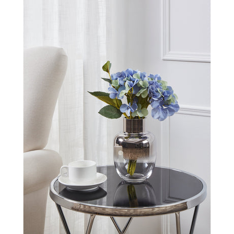 Siranana Glass Vase with mirrored silver shoulder fading to clear glass, holding blue hydrangeas on a round mirrored side table beside a cream armchair.