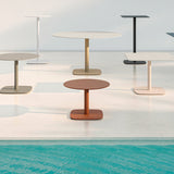 Sirkel round aluminium garden side table with terracotta top and square base, shown poolside among other round tables in white, beige, grey and black.