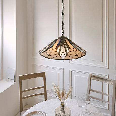 Larkbury 3 Light Tiffany pendant with a wide leaded glass shade in geometric multicoloured panels, hung on a black chain above a marble dining table.