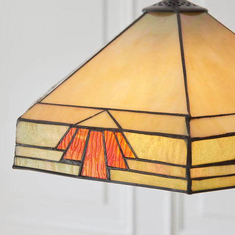 Close-up of the Tiffany Willowmere 3 Light Pendant shade in multicoloured leaded glass with geometric cream, green and orange panels on a dark metal frame.